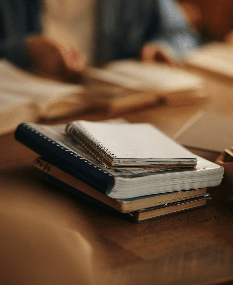 Stack of notebooks on a wooden desk.