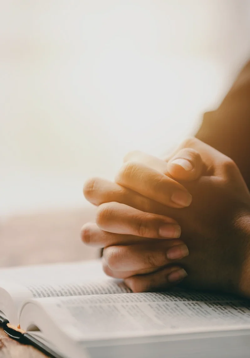 Hands clasped over an open book